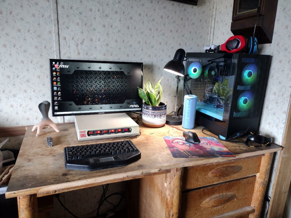 my fresh PC build hooked up to a monitor with no stand. I'm using a Bluetooth speaker for audio and have a keyboard out of a police car. I had to cut a drawer out of the desk to get my knees underneath because it's too short. Oh. and I almost forgot about the ancient surge protector.
