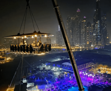 Fancy food bar suspended by a crane with the city lights in the background: