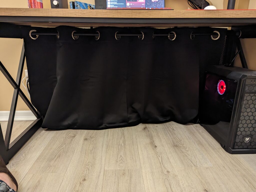 It ain't stupid if it works. A lazy man's approach to cable management. Curtain rod + cheap black curtain.
