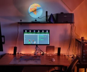 First timer: My cosy corner. I care a lot about light temperature. Pine desk, Fractal Design Focus G tower, Akko CS Jelly Purple keyboard. SSI:s "Curse of the Azure Bonds" onscreen.