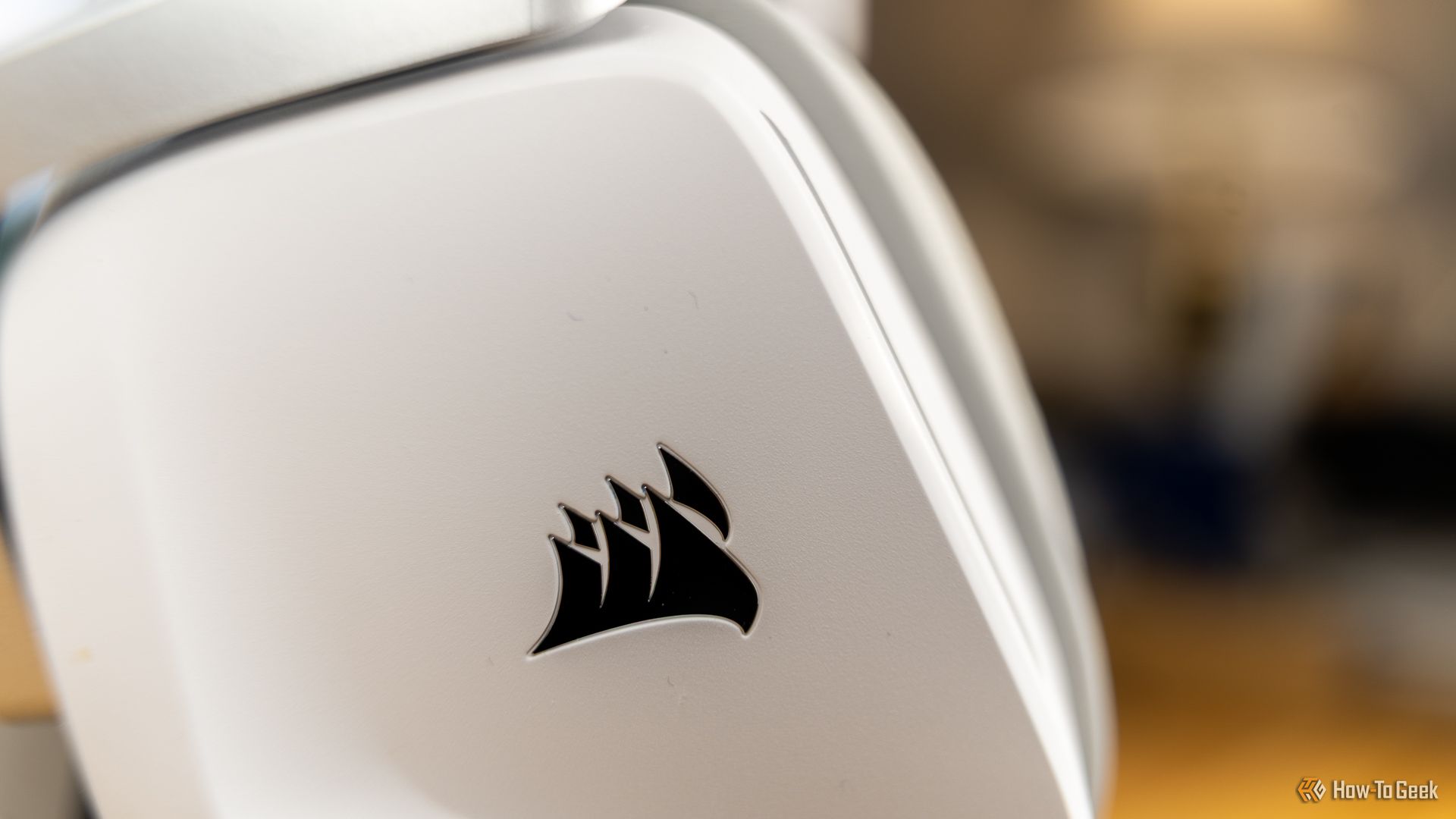 A close-up of the CORSAIR logo on the side of the white CORSAIR Void Wireless V2 gaming headset.