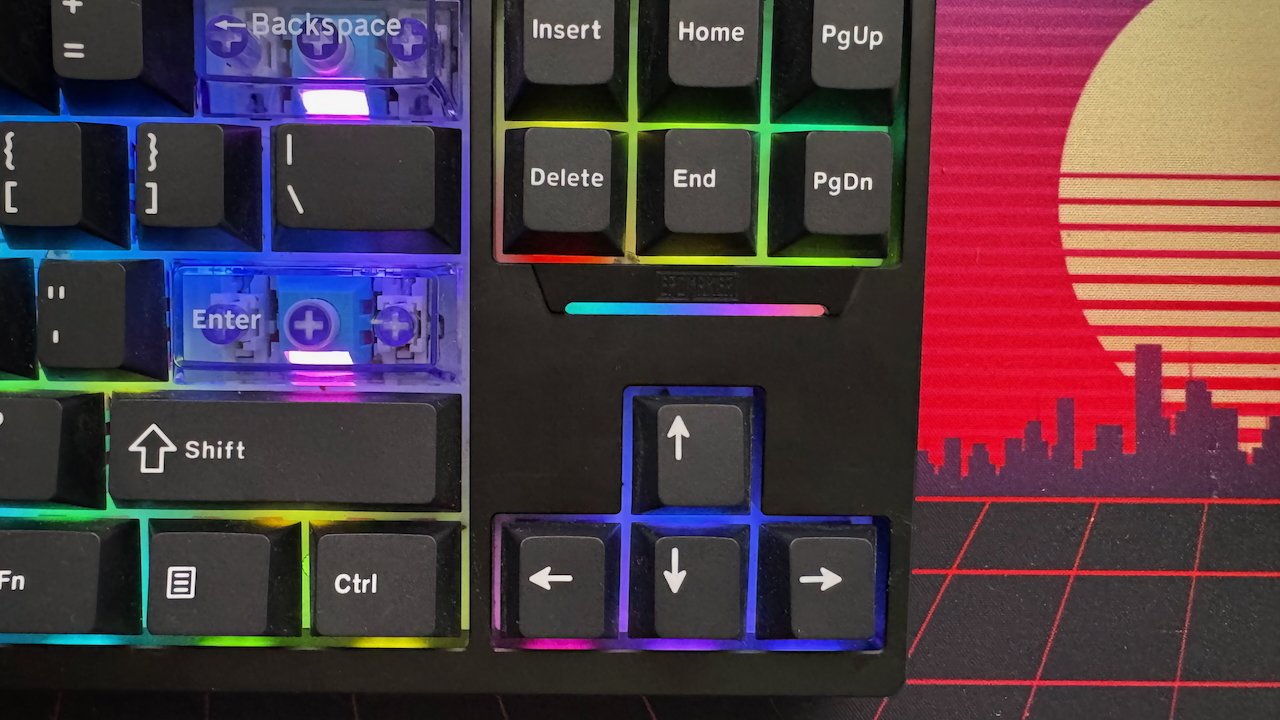 Mechanical keyboard close-up with rainbow backlighting and visible key switches, set against a retro-style sunset cityscape background.