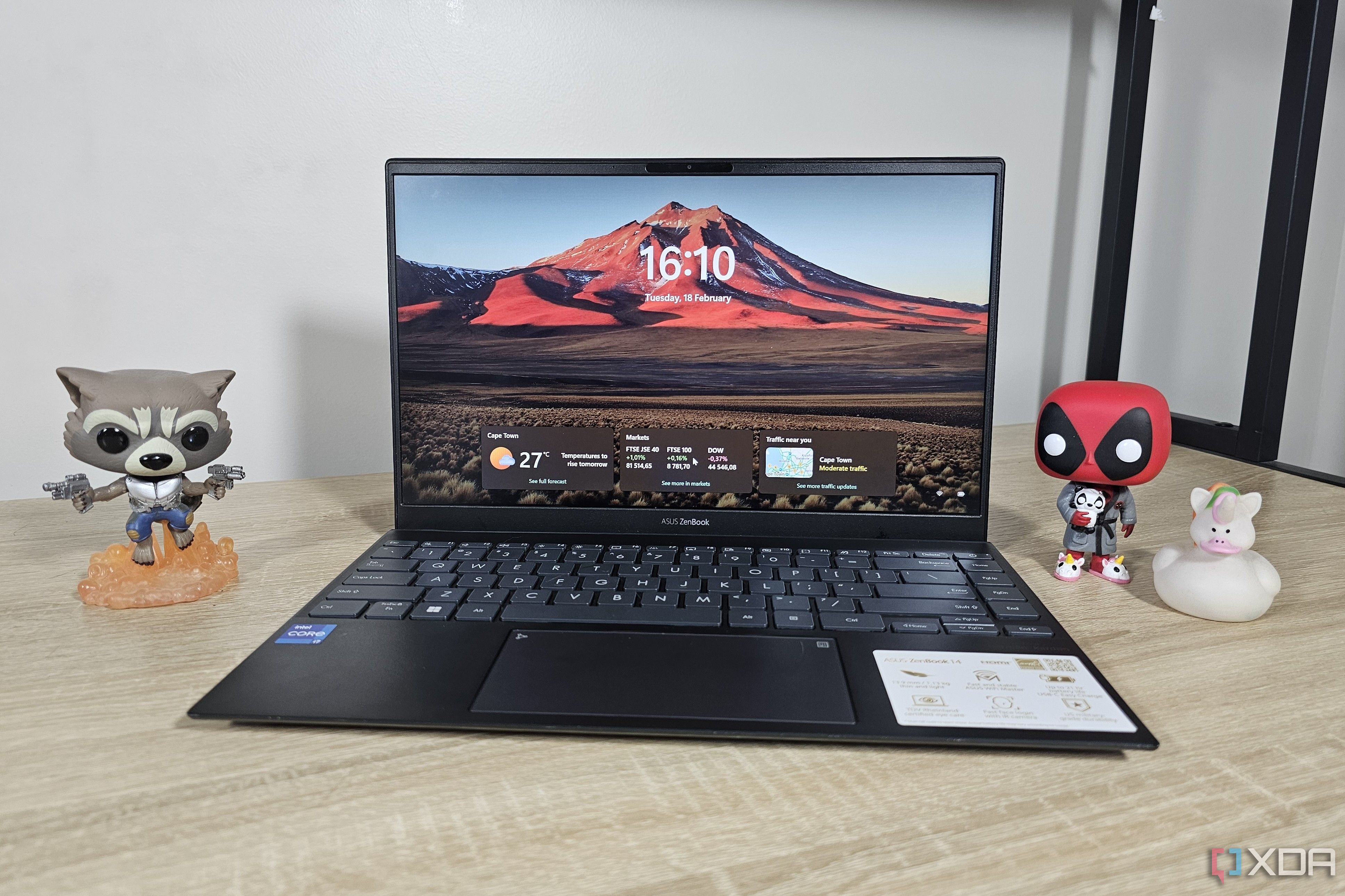 a windows 11 laptop on a desk with various figurines