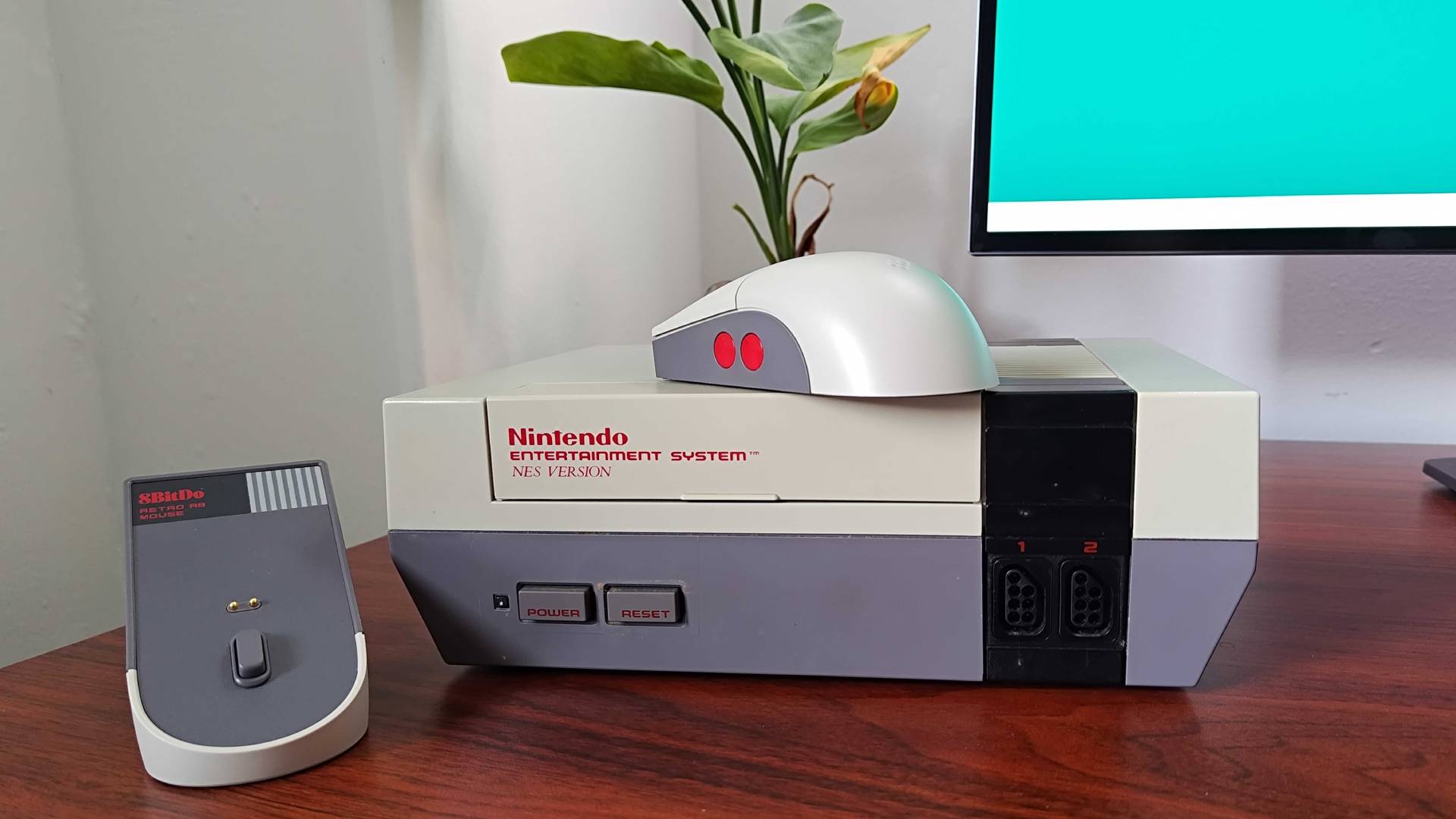 8Bitdo Retro R8 mouse sitting on top of next with dock charger on left.
