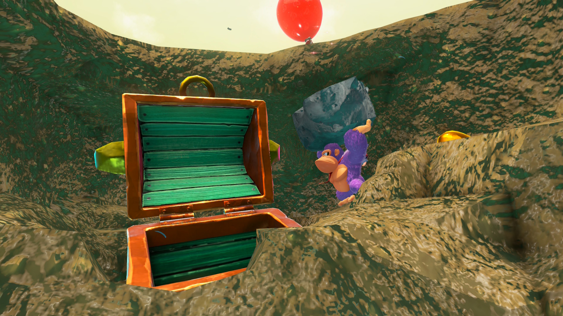 DK in Donkey Kong Bananza wearing a grumpy expression while holding a rock, standing next to an empty treasure chest with a red balloon over his head