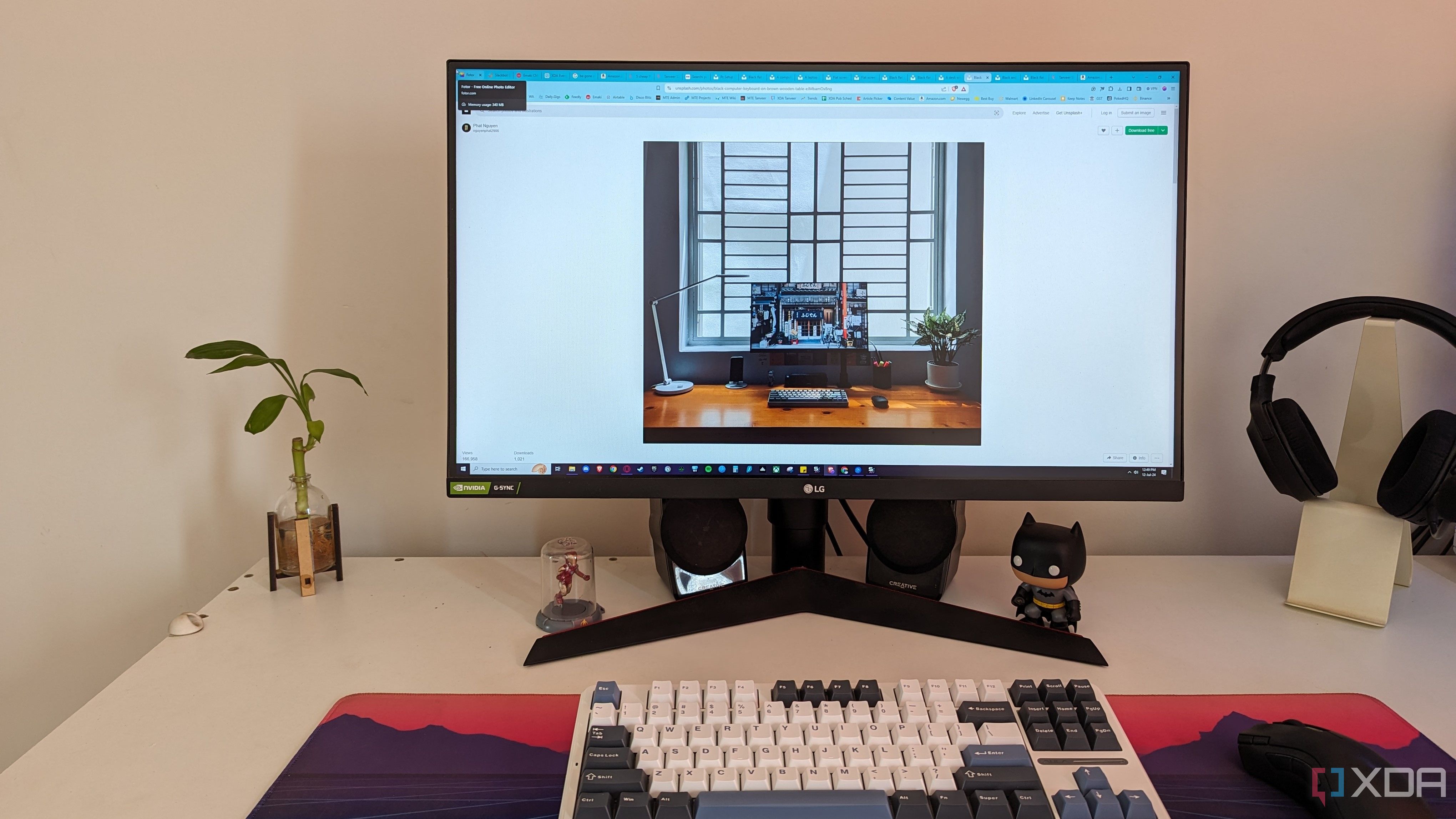 A PC setup with a plant on the desk next to the monitor and keyboard