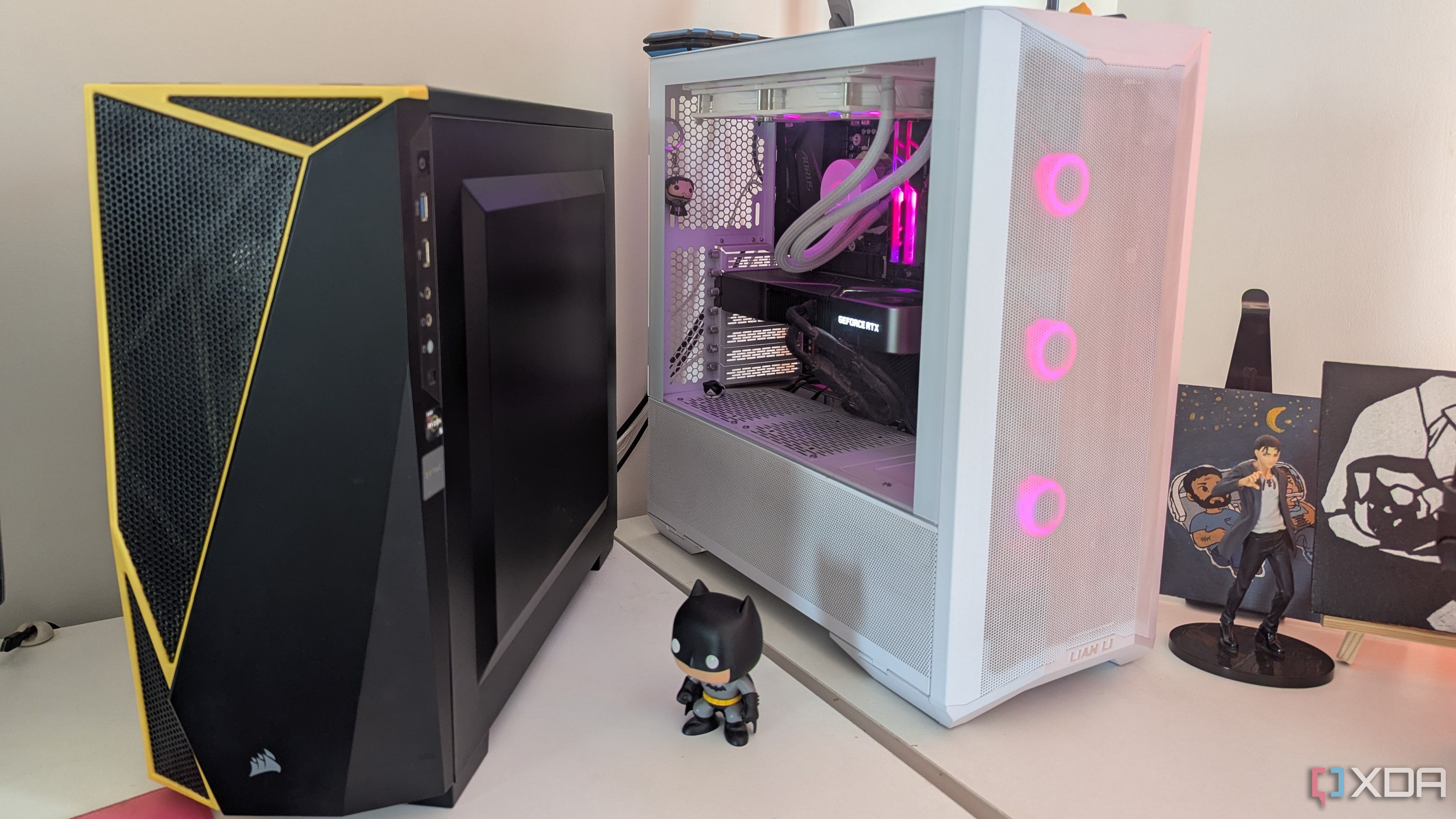 A black and a white gaming PC placed side by side on a white desk