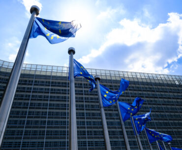 The EU flags flutter in the wind in front of the Berlaymont, the EU Commission headquarter on June 16, 2023 in Brussels, Belgium. The Flag of Europe, adopted on December 9, 1955, is a flag decorated with twelve five-pointed gold stars, one of the points pointing upwards, arranged at equal distance in a circle on a field of azure. It represents solidarity and union between the peoples of Europe.