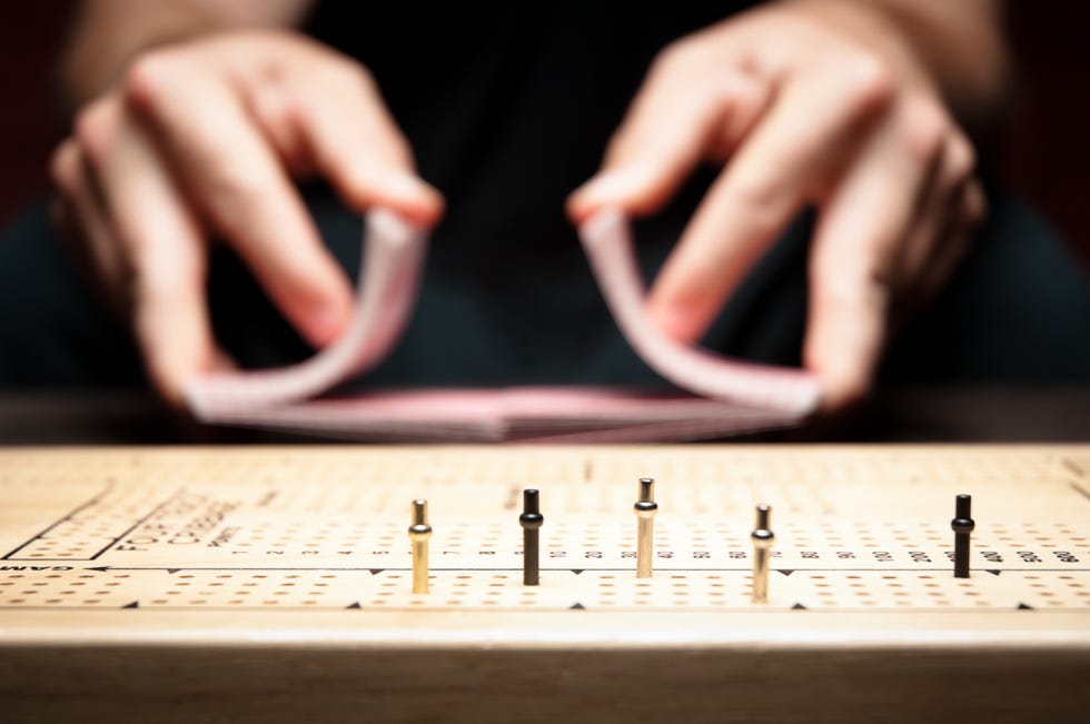 cards being shuffled during a cribbage game with the cribbage board with pegs in it in the foreground cards being shuffled during a cribbage game with the cribbage board with pegs in it in the foreground