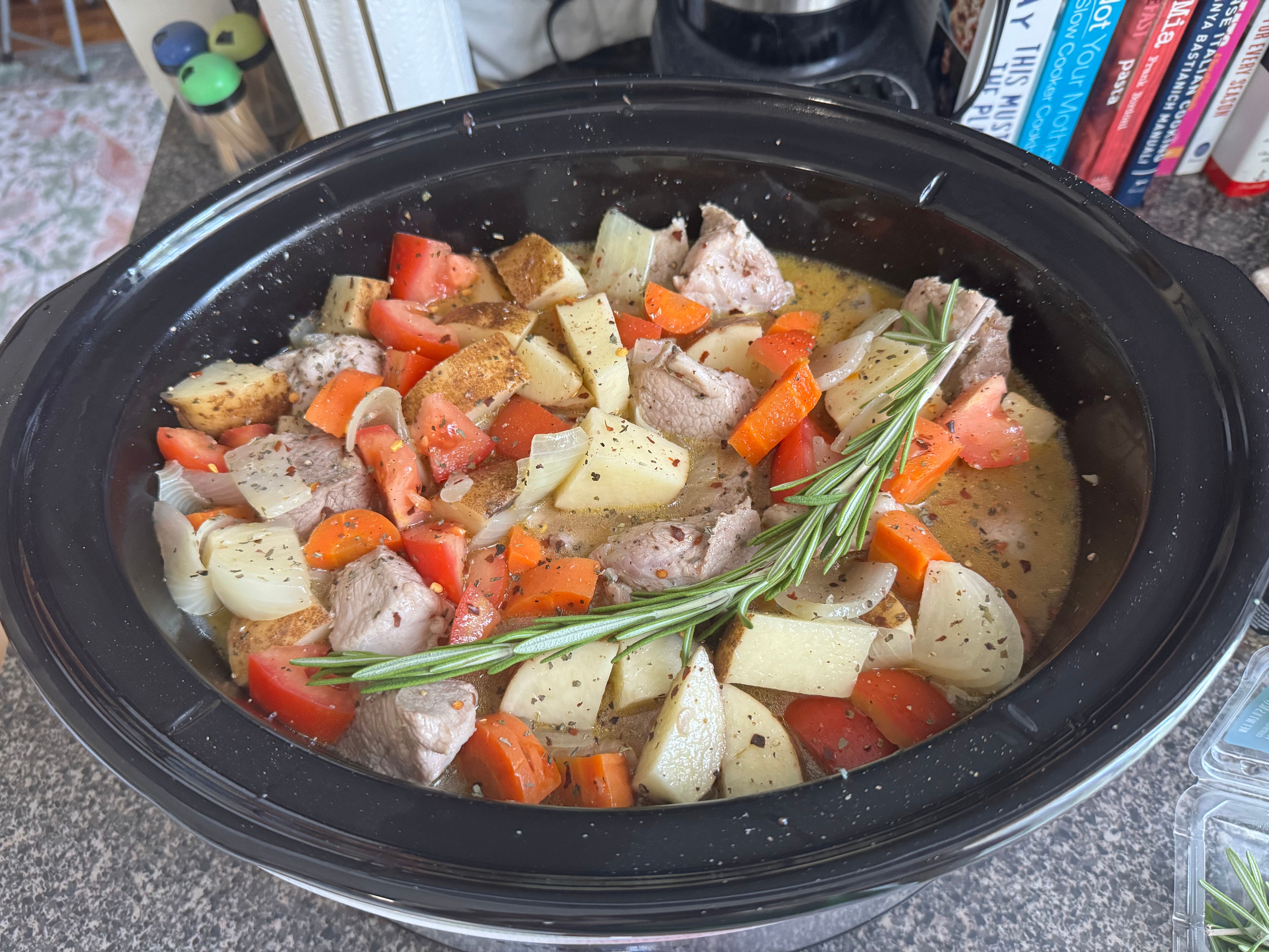 Uncooked pork spezzatino sits in a slow cooker.