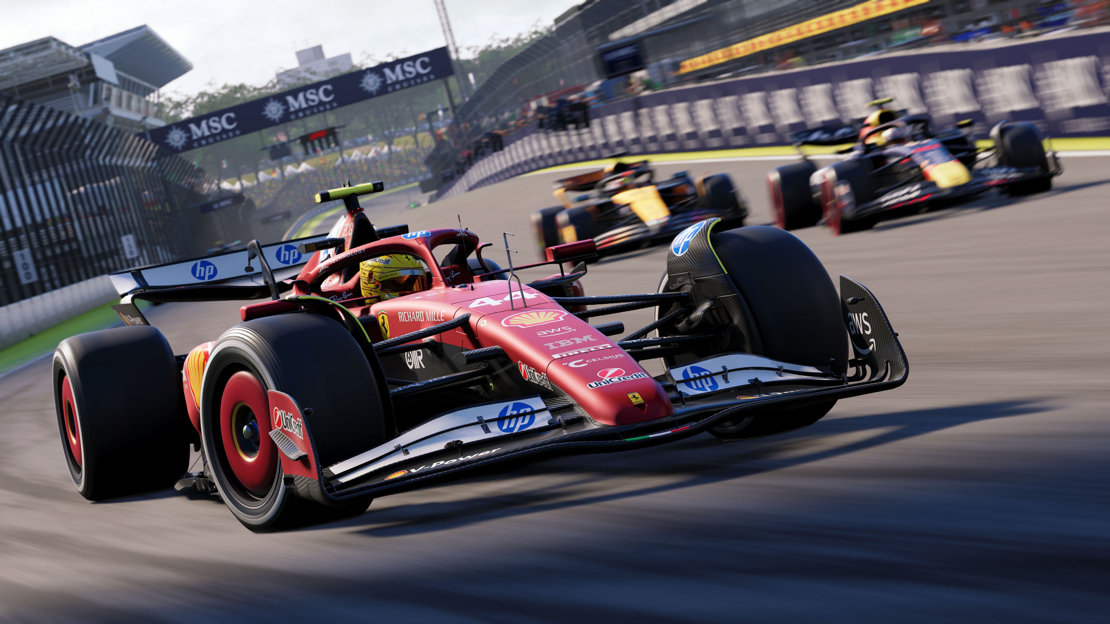 Three F1 cars racing down a track, with a red Ferrari leading.