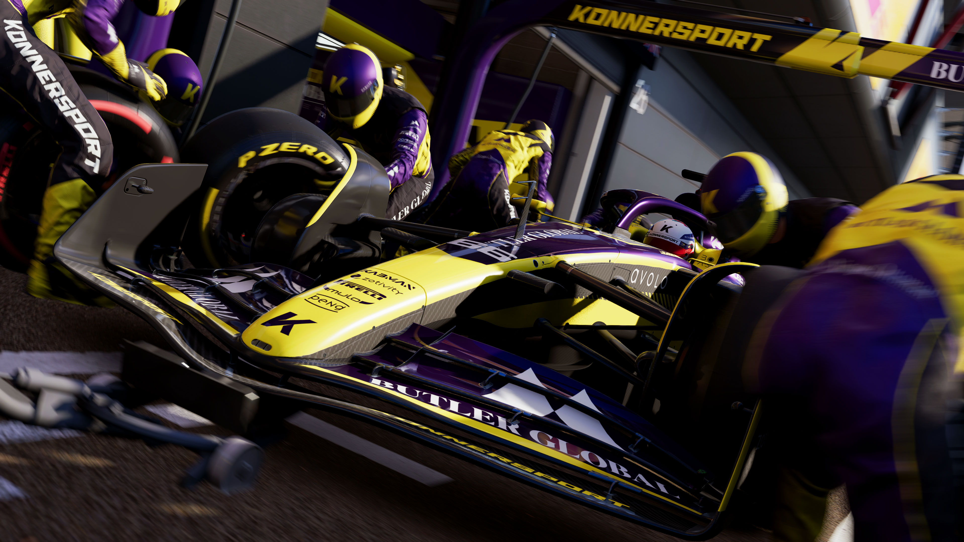 A Konnersport F1 Car featuring a yellow livery in the pits, undergoing a wheel change by the pit crew