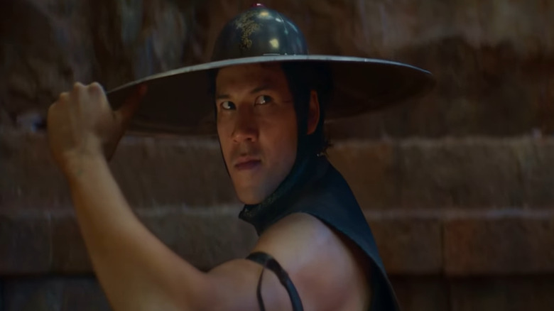 Kung Lao (Max Huang) holds the brim of his bladed hat in Mortal Kombat (2021)