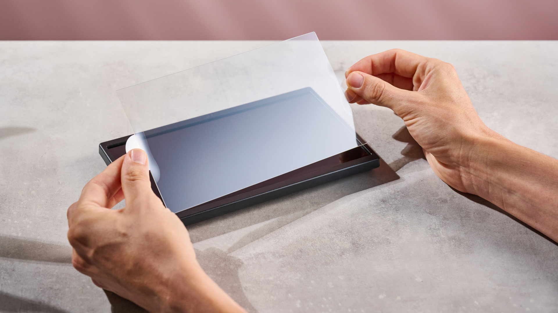 A man lifting and preparing to apply the Belkin Tempered Glass Anti-Reflective Screen Protector to the Nintendo Switch 2.