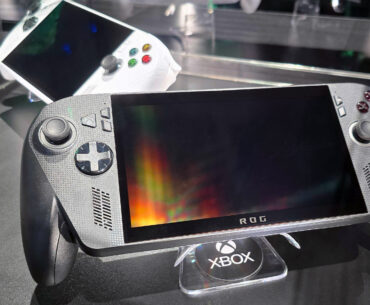ASUS ROG Xbox Ally X (black) and ROG Xbox Ally (white) in a glass display case at Gamescom in August, 2025.