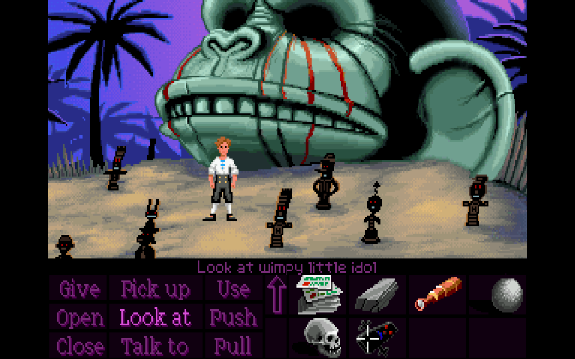Guybrush stands in front of a giant monkey head statue in The Secret of Monkey Island. 