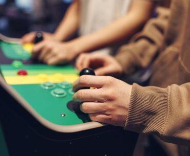 Teenagers playing retro arcade machines