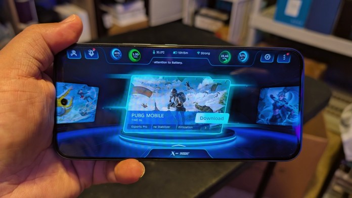 A person holding a smartphone displaying the PUBG Mobile game interface, showcasing battery status, CPU usage, and RAM usage indicators.