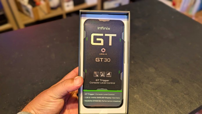 Close-up of the Infinix GT 30 smartphone packaging, held in a hand, showcasing the front of the box with branding and product features highlighted.