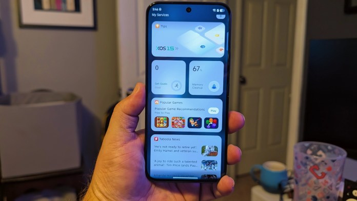 A hand holding an Infinix GT 30 smartphone displaying the XOS 15 interface, featuring tips, memory cleanup, and popular game recommendations on the screen.