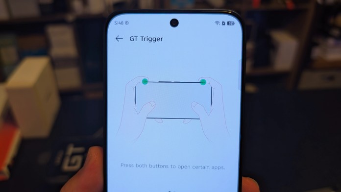 Close-up of the Infinix GT 30 smartphone screen displaying the GT Trigger feature, with hands demonstrating button placement to open apps.