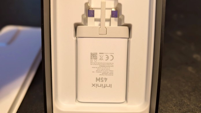Close-up view of the Infinix 45W fast charger displayed in its packaging, with the prongs extended and technical specifications visible on the side.