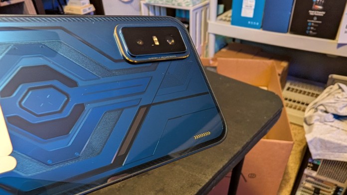 Close-up view of the Infinix GT 30 smartphone's back panel featuring a blue cyberpunk-inspired design, showcasing geometric patterns and the camera module.