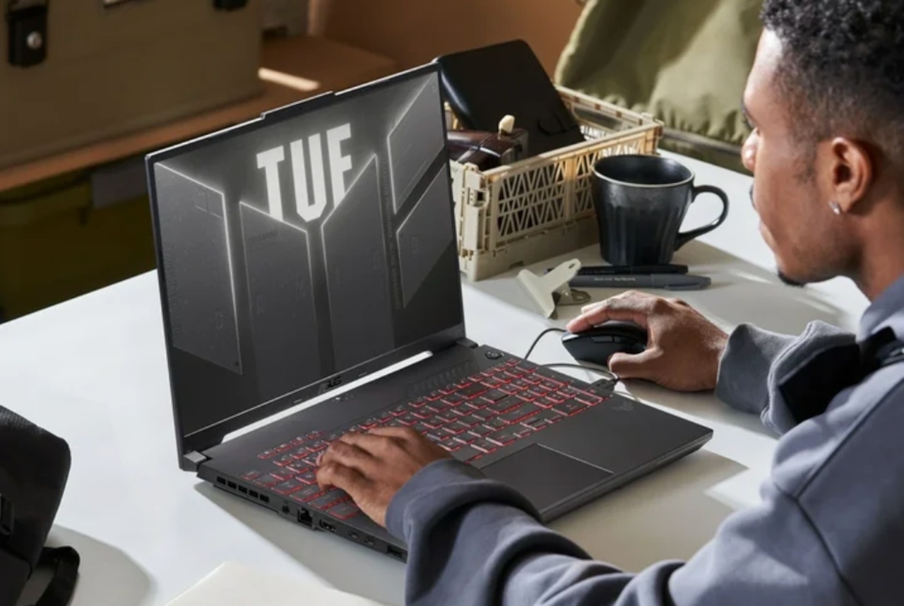 A product image featuring a young man using the 16-inch ASUS TUF A16 Gaming Laptop on a while table top.
