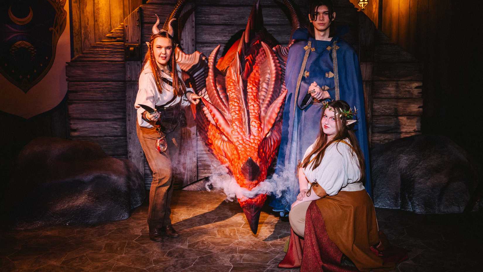 Actors from Dungeons & Dragons: The Immersive Quest stand around the steaming head of the red dragon Ashardalon