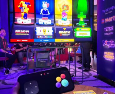 A TV screen shows four players jumping into a party game with Lego characters.