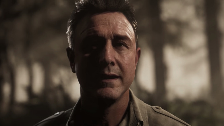 Chris Hackett stands solemnly in a forest in 