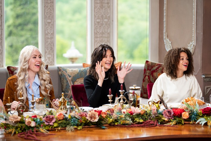 Ellie, Jade and Roxy looking surprised as they sit at The Traitors breakfast table.