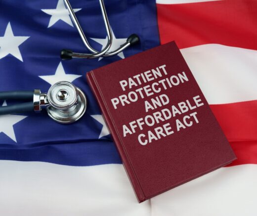 A book titled Patient Protection and Affordable Care Act with a stethoscope, both on top of an American flag.