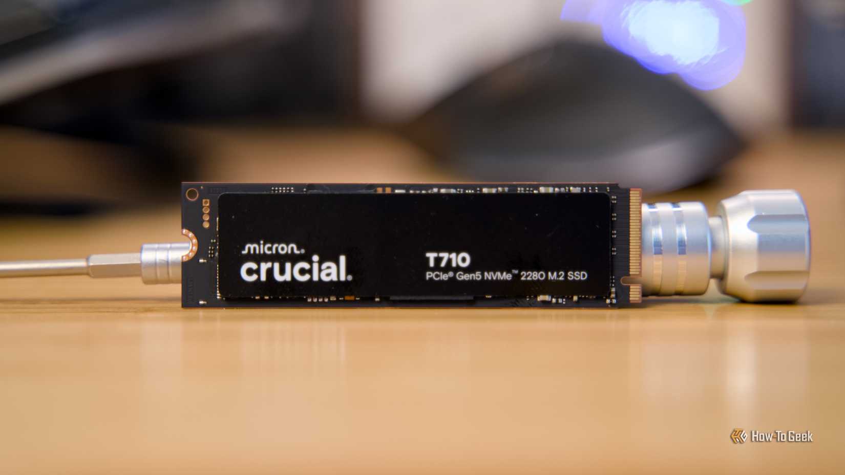 The Crucial T710 NVMe SSD propped up on a desk by a metal screwdriver.