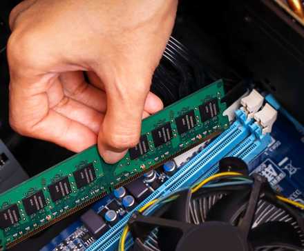 Someone installing a stick of RAM in a computer.
