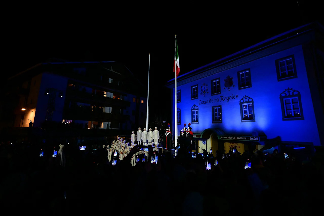 Performers take part in the Italian national anthem as people hold smartphones during the opening ceremony of the Milano Cortina 2026 Winter Olympic Games, at Piazza Angelo Dibona in Cortina d'Ampezzo, northern Italy, on February 6, 2026. (Photo by Stefano RELLANDINI / POOL / AFP via Getty Images)