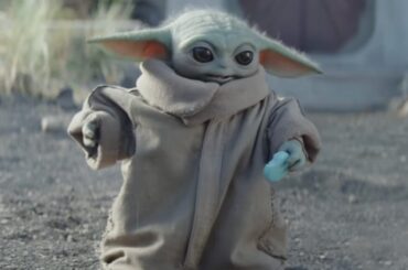 little green yoda-like alien holding a light blue sweet treat shaped like a small cookie.