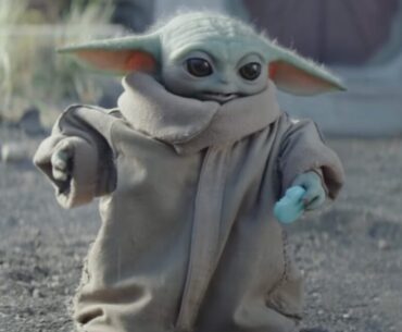 little green yoda-like alien holding a light blue sweet treat shaped like a small cookie.