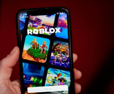 A smartphone displaying the Roblox logo and gameplay images.