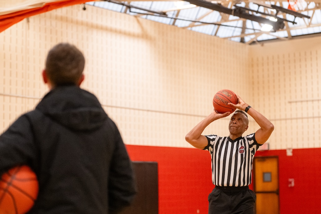 Adrian Dantley, NBA Hall of Famer, shoots free throws at Upper County Community Center while talking with a recreational basketball league parent after refereeing a game in Gaithersburg, MD.