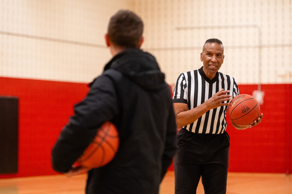 Adrian Dantley, NBA Hall of Famer, shoots free throws at Upper County Community Center while talking with a recreational basketball league parent after refereeing a game in Gaithersburg, MD.