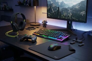 Assorted gaming products arranged on a deck with a gaming monitor.