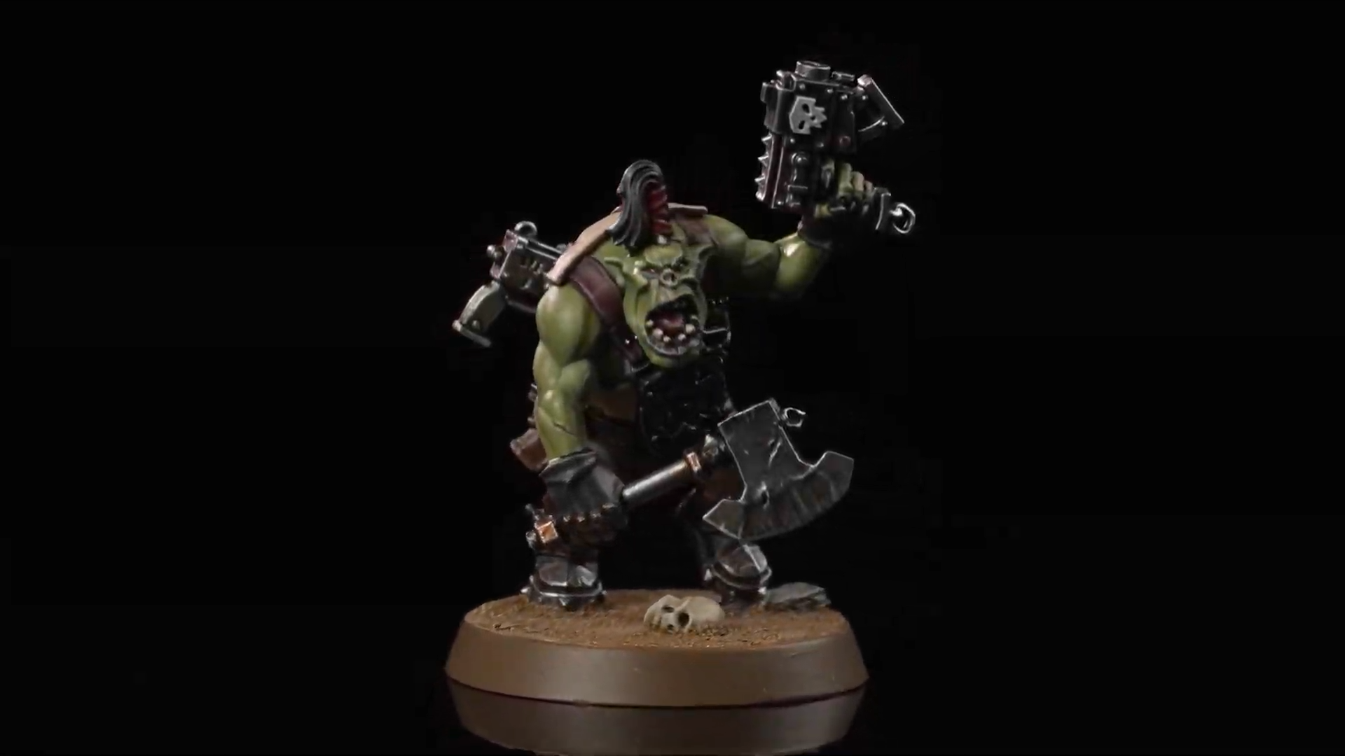 An Ork Boy weilding an axe and a pistol against a dark background