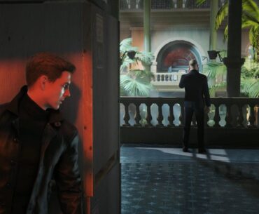 An in-game screenshot of a man hiding behind a corner before ambushing another man on the phone.