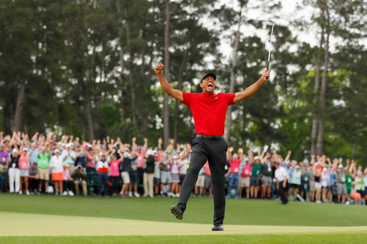 American golfer Tiger Woods celebrates after sinking his putt on the 18th green.