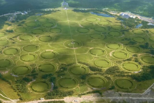 aerial view of a lush green flat landscape dotted with circles representing the entrances to individual silos
