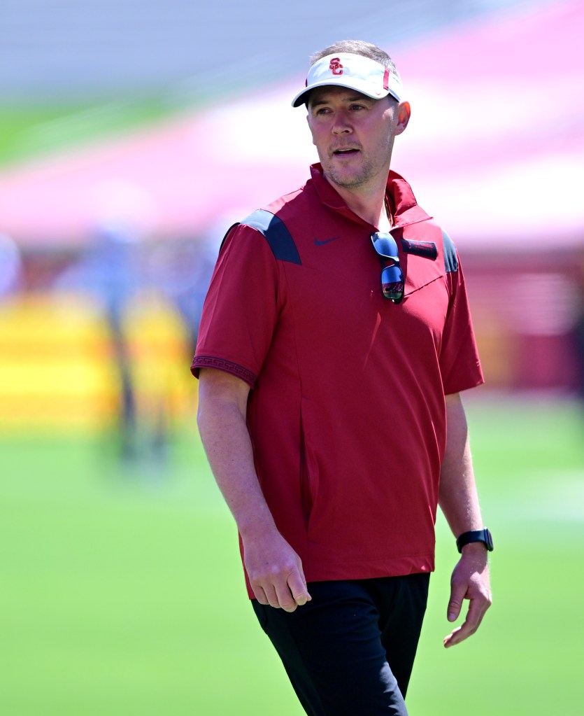 A man in a red USC shirt and visor looks to the side.
