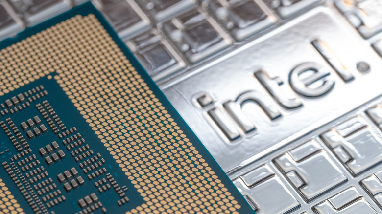 A computer chip rests next to the Intel logo, which is embossed into a piece of metal