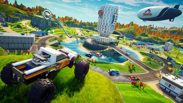 A Lego 4x4 truck is perched on top of a hill that overlooks a landscape filled with grass, and other Lego cars and structures.