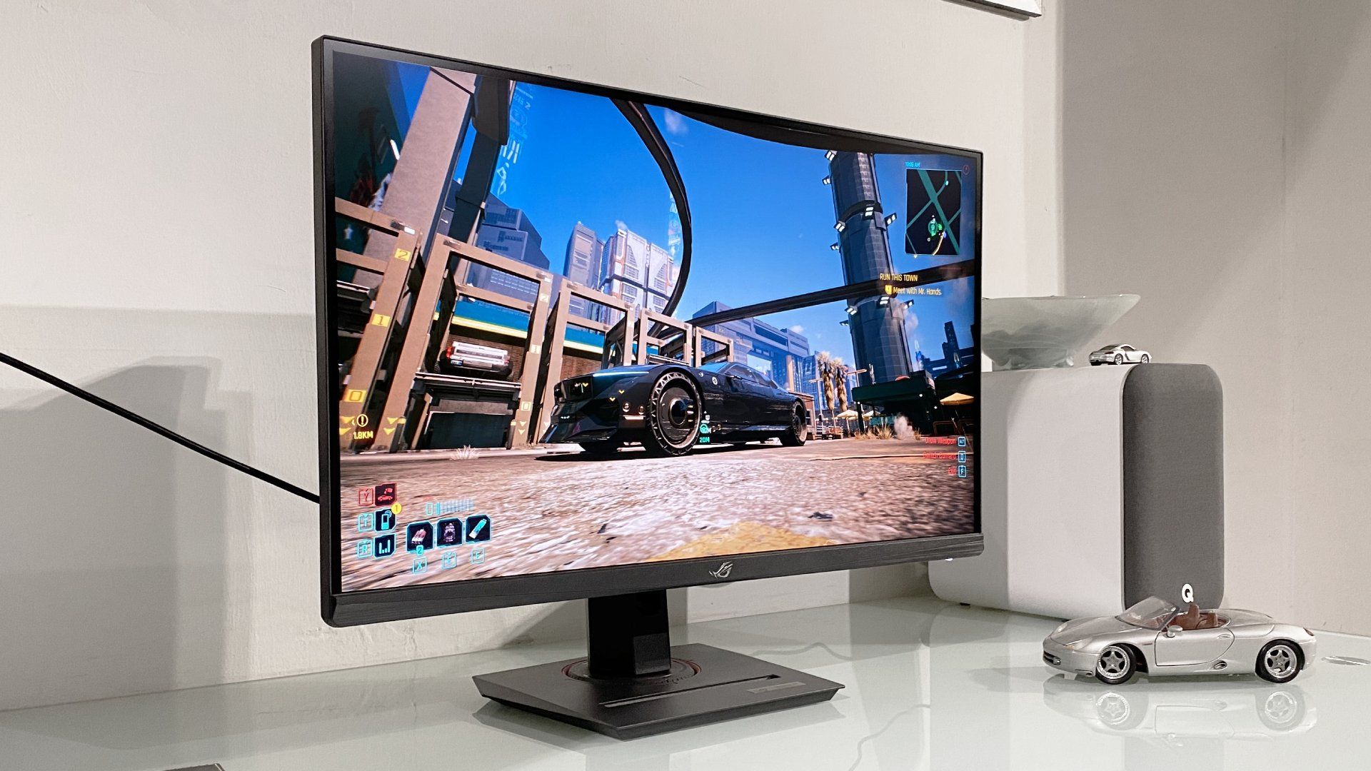 This “punchy” 4K 27-inch PC gaming monitor switches to 1080p and 320Hz for esports, and it’s even better with this price drop A sleek gaming monitor displays a vibrant cityscape from a video game. Next to it, a model car and speaker sit on a white desk, creating a modern tech vibe.